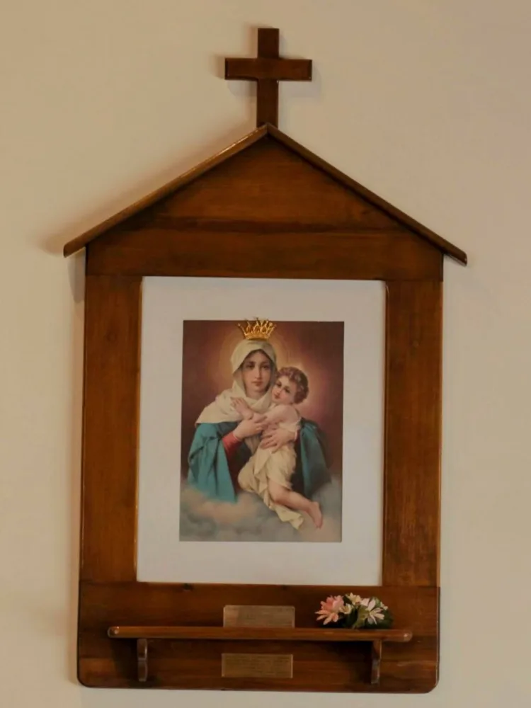 La imagen de la Mater coronada, en una capillita de madera con cruz, entre dos estaciones del Vía Crucis
